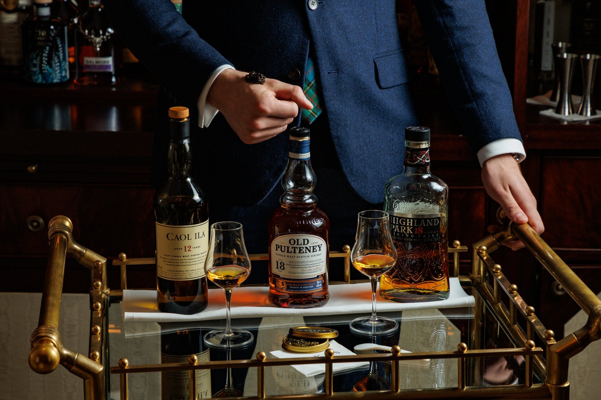 A brass drinks trolley at The Delany Drawing Room with Caol Ila 12, Old Pulteney 18 and Highland Park 18, two nosing glasses and two tins of Attilus caviar.